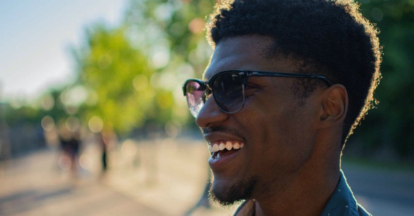 man blue shirt smiling outside