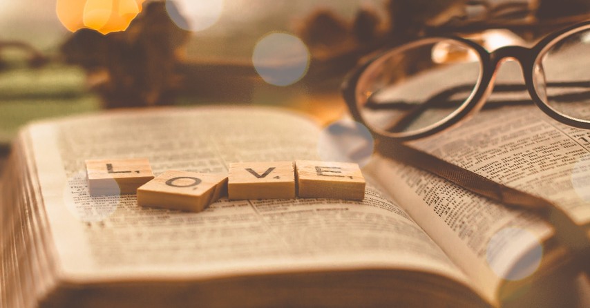 Bible opened with scrabble pieces that say love and Glasses on it