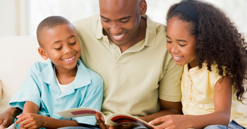 dad reading book with young son and daughter