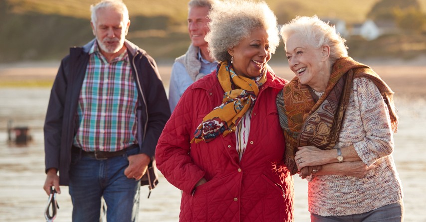 happy multicultural senior friends walking on beach, phileo love