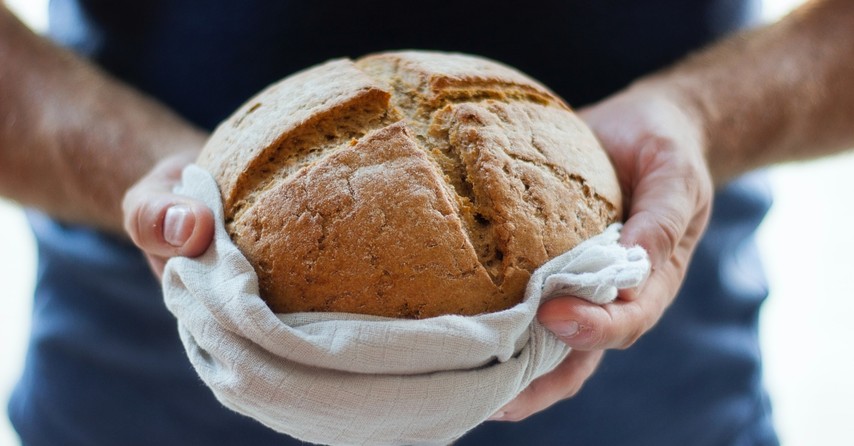 A person holding out a loaf of bread