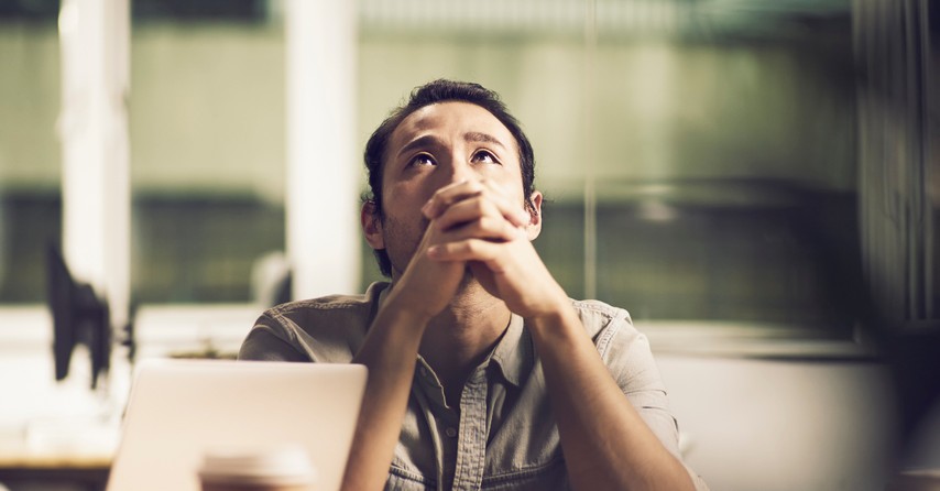 asian businessman hands folded in prayer looking up for hope