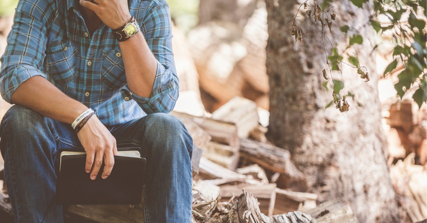 A pondering man with a Bible in the woods, Leading in unprecedented times