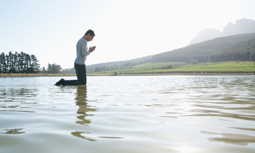 man kneeling on water praying