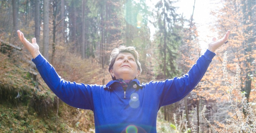 senior woman with hands uplifted in praise outdoors