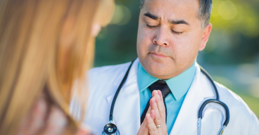 doctor intercessory praying with woman