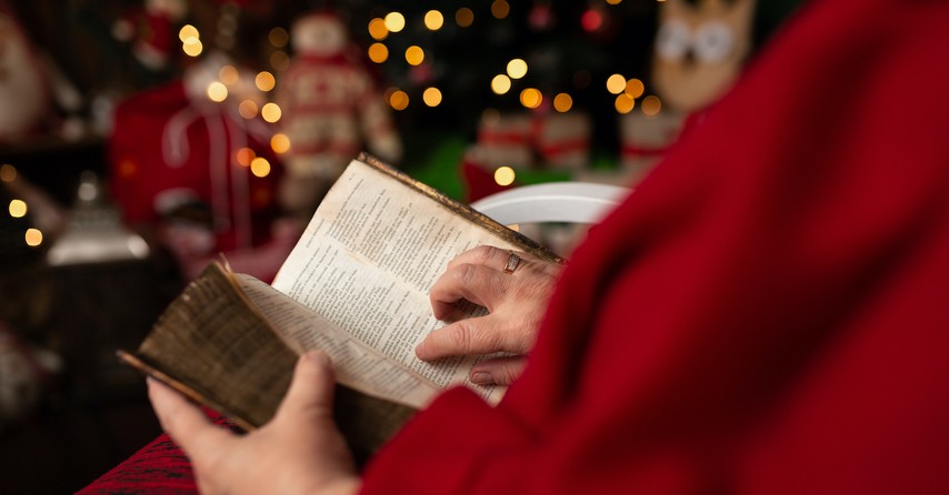 Person reading a Bible near a Christmas tree, things to notice when you read Luke 2