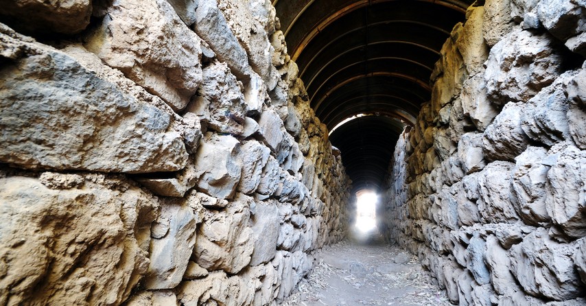 stone wall leading to narrow opening with bright light, narrow is the gate