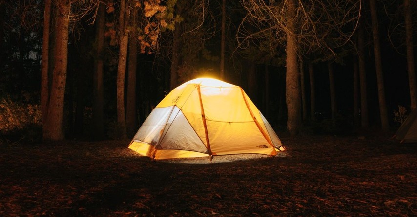 A brightly lit tent in the woods at night