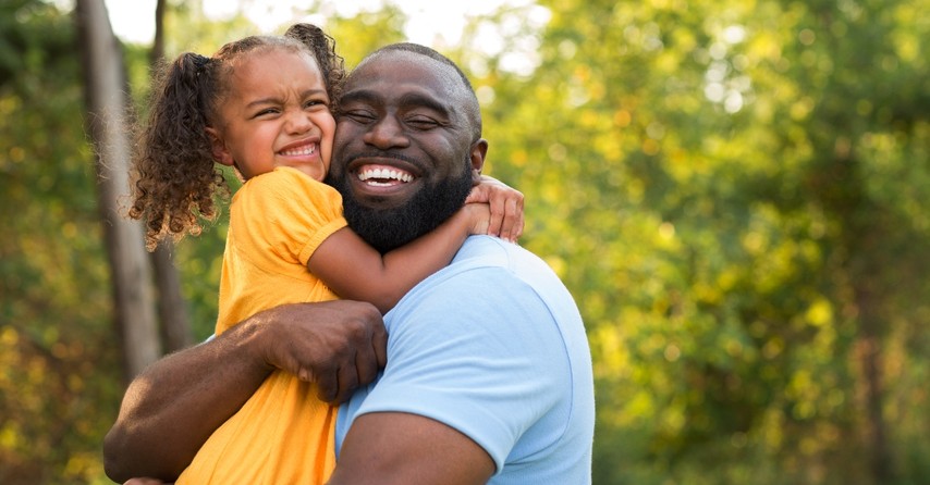 dad holding and hugging daughter outside smiling big looking happy