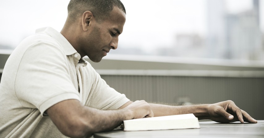 Man smiling as he reads the Bible