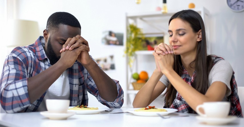 couple praying together at dinner