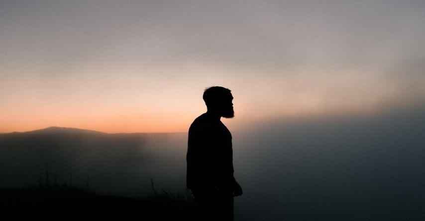 man in black jacket against sunset background, in the world but not of the world