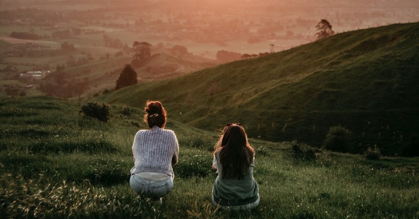 two women looking at townscape from pasture, in the world but not of the world