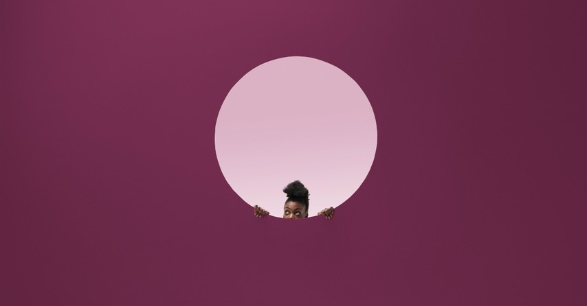 Woman peeking out of a hole in a purple wall, hidden