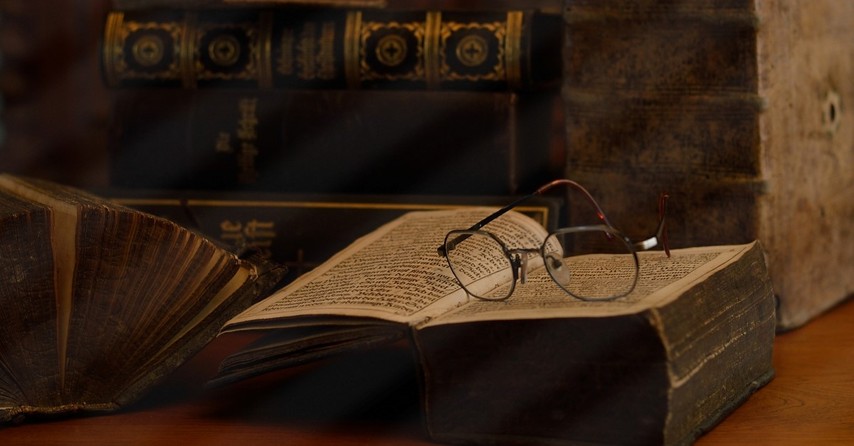 glasses on an old book in room full of books