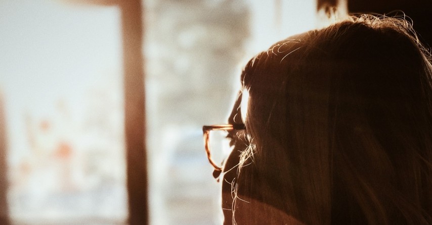 thoughtful woman with glasses looking out window, prayers bible verses about gratitude