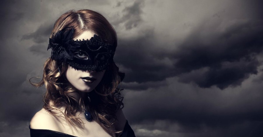 woman in seductive halloween blackbird feather mask cloudy sky