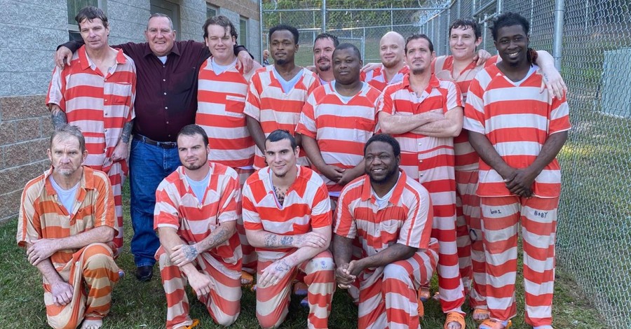 Several men gathered in jumpsuits, Inmates are baptized at Mississippi jail