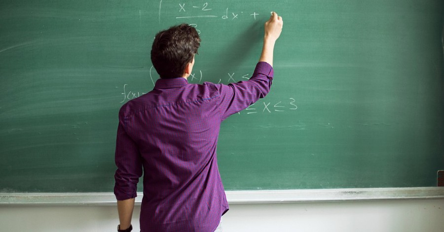 A person writing on a chalkboard, teacher files lawsuit against county after he is suspended for his views