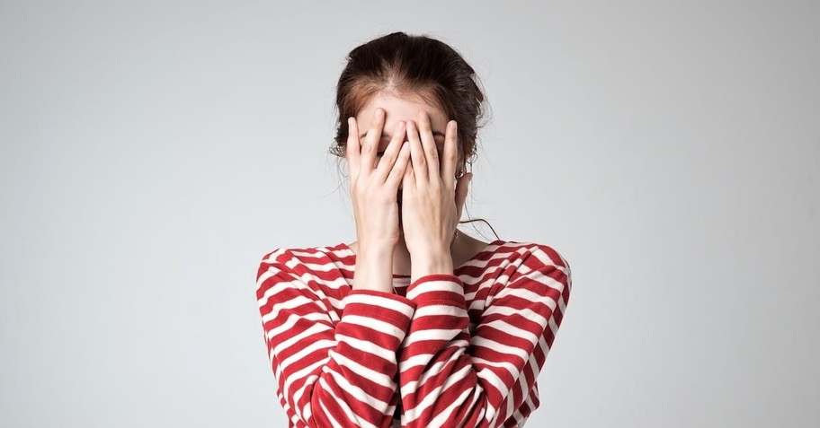 woman covering her face in shame