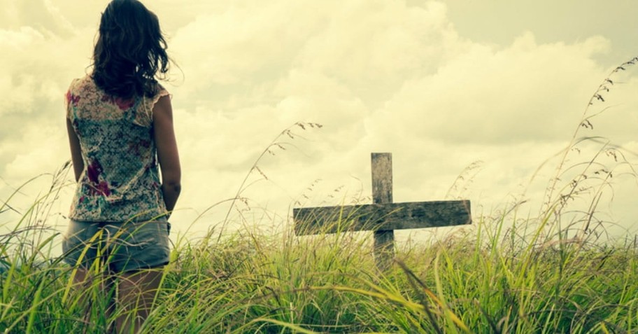 Girl in a field with a cross