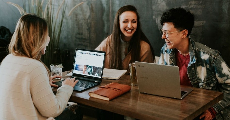 Three people at table laughing, prayers for end of semester