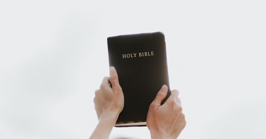 Hands holding a Bible up in the air
