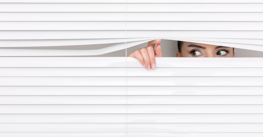 Suspicious woman looking through blinds