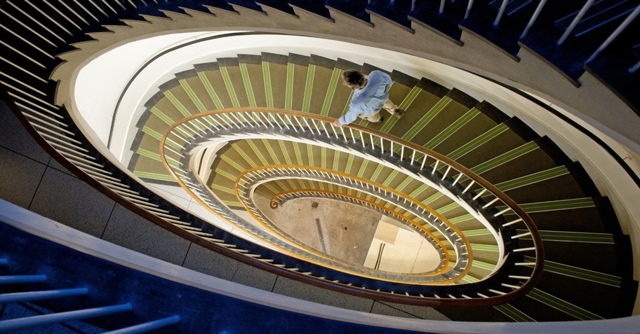 Man walking down steep spiral stairs