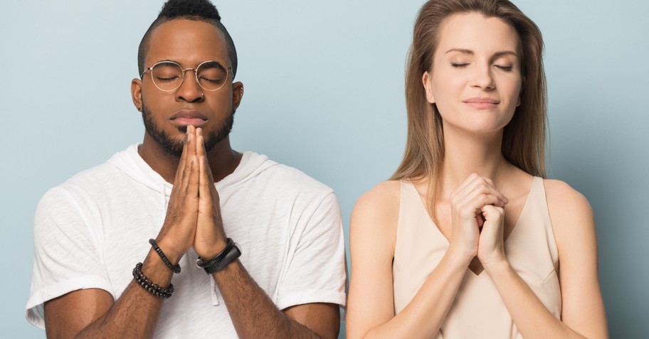 man and woman standing in prayer eyes closed