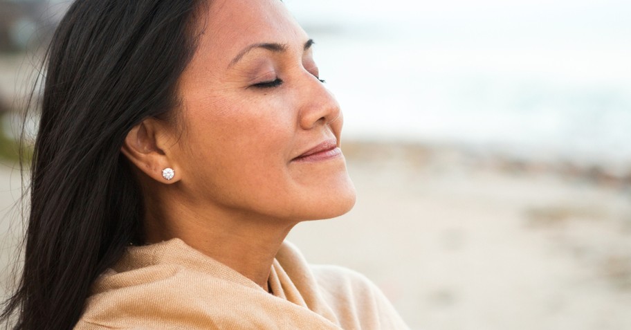 woman eyes closed wrapped in shawl on beach in peaceful praise