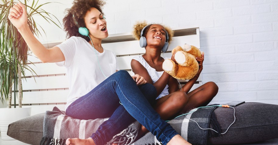 joyful mom and daughter singing praise songs with headphones on