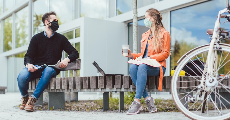 young adults sitting on bench with masks