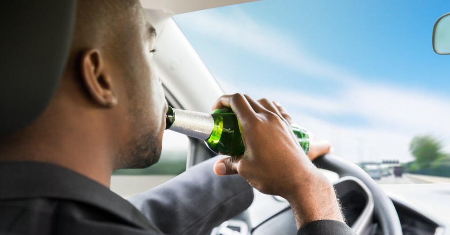 man drinking alcohol while driving