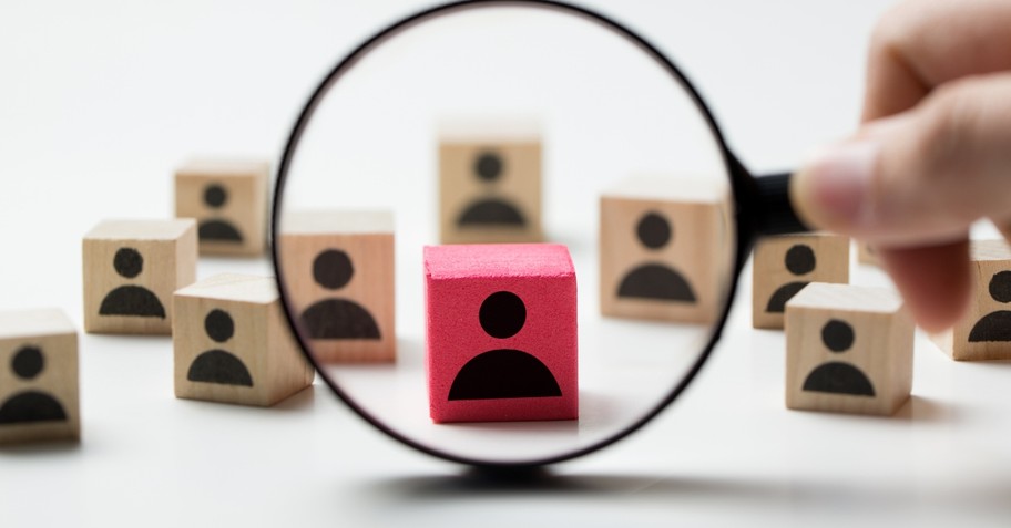 magnifying glass on red person cube amid plain person cubes