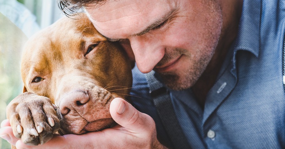 man snuggling with dog