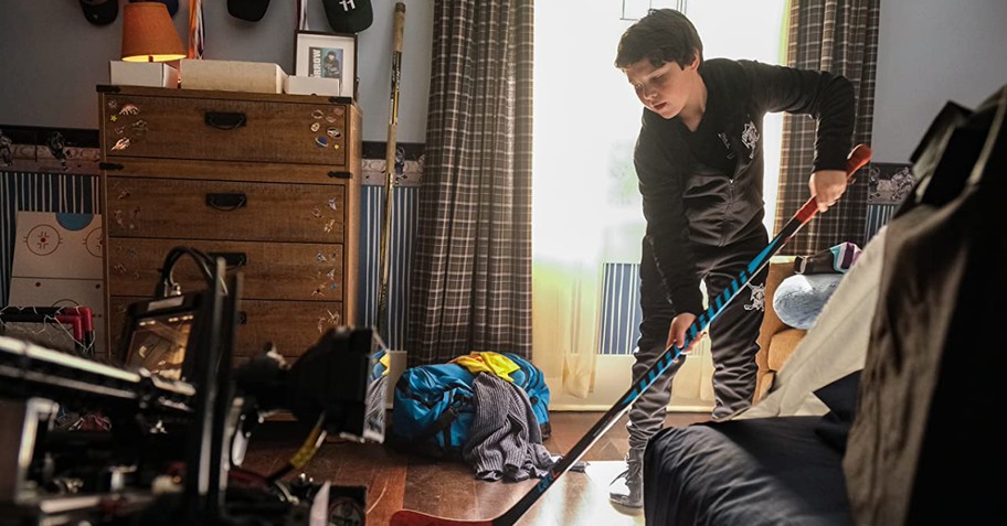 a young boy playing hockey in his room