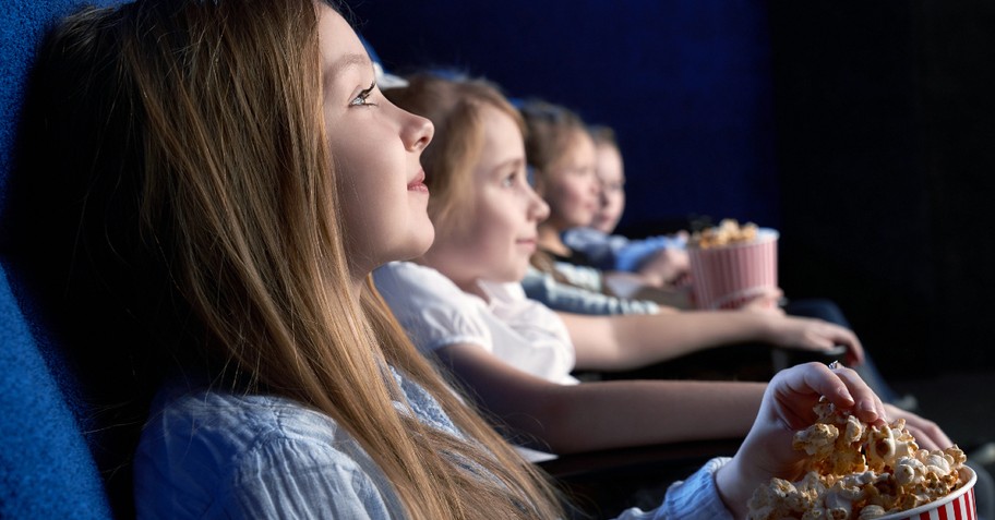 little girl eating popcorn at movie theater