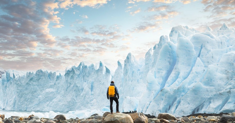 A lone hiker stands gazing at a glacier in the far north