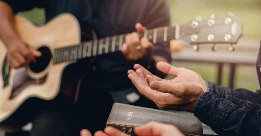 a person playing a guitar and a person holding a Bible