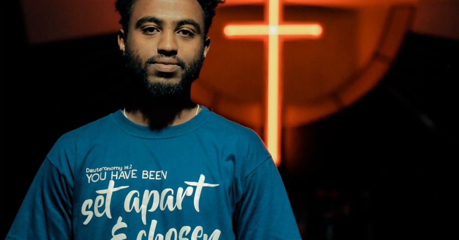 man with set apart tshirt on standing in front of glowing cross