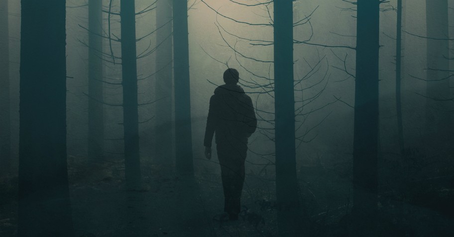 man walking through dark forest