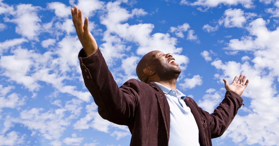 man praising arms out and face toward blue sky