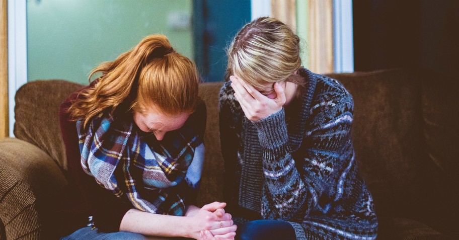 Two sad women, crying and praying together