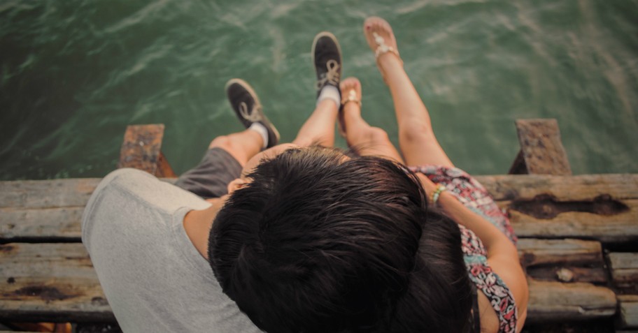 Couple hugging while sitting on a dock