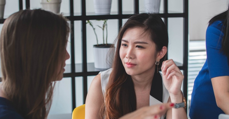 Young woman in an office listening to a coworker