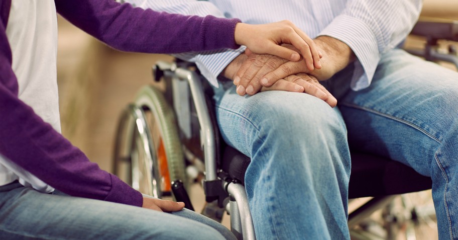 Woman holding the hand of someone in a wheelchair