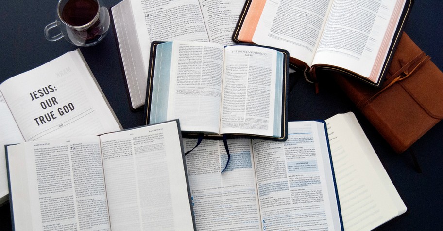 A pile of open Bibles on a desk - get behind me satan meaning