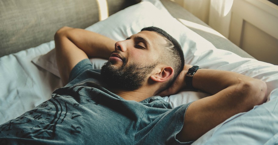 A man asleep with his hands behind his head